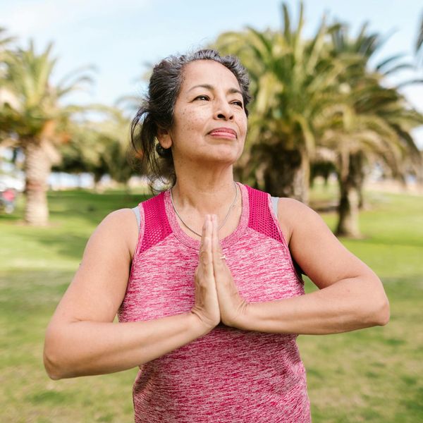 Person smiling and stretching outdoors in a park.